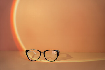 Vision glasses with black frames under orange light.