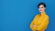 © qntn - Confident businesswoman in vibrant yellow blouse posing with assurance against a serene blue background, exemplifying professional poise and determination - AI generated