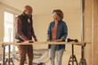© Jacob Lund - Collaborative home renovation project: Diy couple discussing remodeling plans with mature carpenters