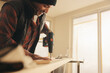 © Jacob Lund - Do it yourself: Happy man using a drill gun on wood while renovating his house