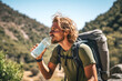 handsome adult enjoying a refreshing drink from a water bottle while hiking in the mountains, exemplifying a healthy and active lifestyle.