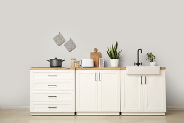 Poster - Interior of modern kitchen with utensils, sink and electric stove on white counters