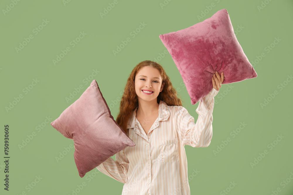 Beautiful young woman with soft pillows on green background