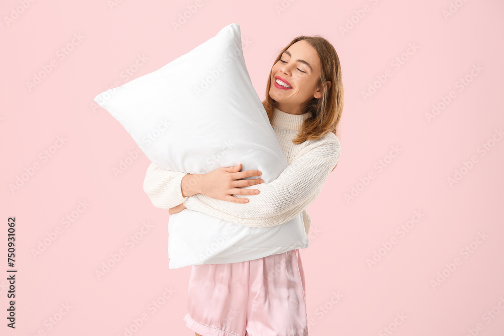Happy young woman with white soft pillow on pink background