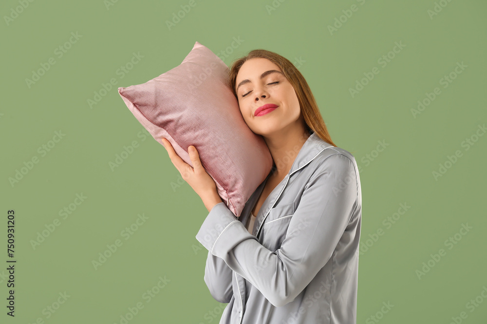 Beautiful young woman with pink soft pillow on green background