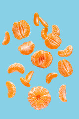 Wall Mural - Flying sweet peeled mandarins on blue background