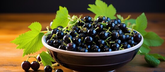 Wall Mural - A closeup of a bountiful summer harvest, showcasing a bowl filled with ripe black berries next to vibrant green leaves.