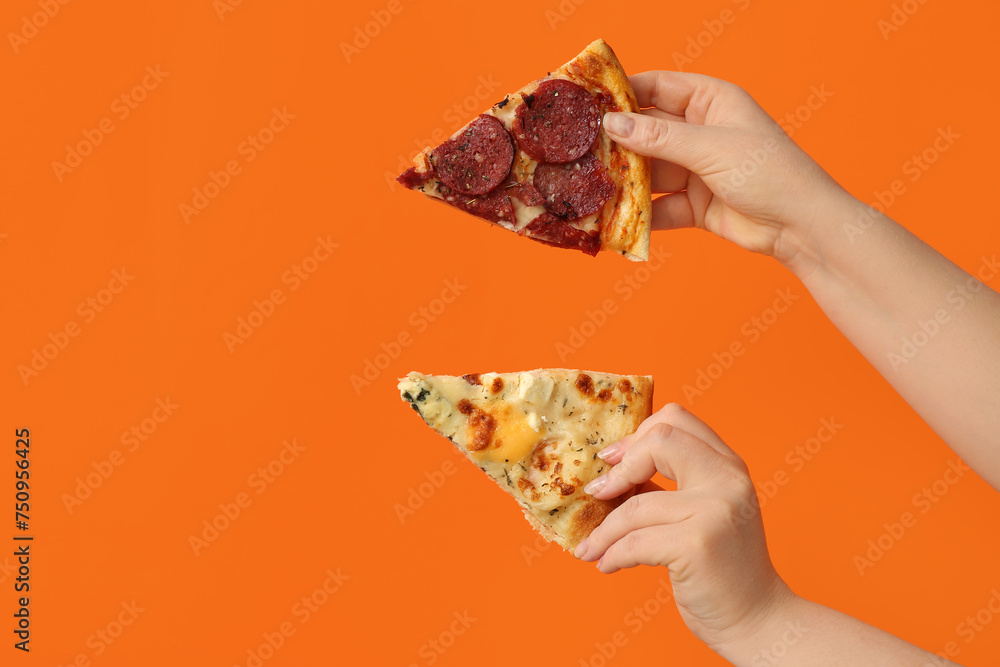Female hands holding tasty pizza slices on orange background