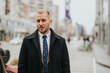© qunica.com - Confident young businessman walking in urban setting, professional lifestyle.