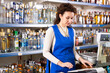 © JackF - Woman works as salesperson in alcohol department of Russian store. Shop employee is warmly waiting for stores visitors at vodka display case.