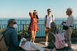 © Jimena Roquero/Stocksy - Group of Tourist chatting in front of panoramic view of the sea