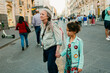 © Jimena Roquero/Stocksy - Grandmother and granddaughter walking on crowded street