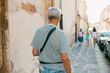© Jimena Roquero/Stocksy - Back of senior man walking on the sidewalk of an old Italian City.