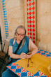 © Jimena Roquero/Stocksy - Senior woman sitting on a colorful outdoor cafe checking her phone