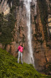 © Luis Herrera/Stocksy - woman traveler in front of a big waterfall