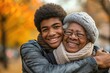 african american Teenage son hugging his senior mother outside in town when spending time together