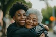 african american Teenage son hugging his senior mother outside in town when spending time together