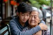 Asian Teenage son hugging his senior mother outside in town when spending time together