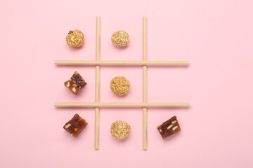 Wall Mural - Tic tac toe game made with sweets on pink background, top view