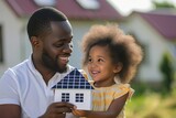 Fototapeta Most - african american little girl with her dad holding paper model of house with solar panels