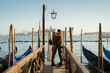 Happy couple kissing near gondolas in Venice
