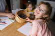 © Serena Burroughs/Stocksy - Happy girl with glasses drawing at her kitchen table at home