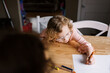 © Serena Burroughs/Stocksy - Happy girl with glasses drawing at her kitchen table at home