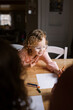 © Serena Burroughs/Stocksy - Happy girl with glasses drawing at her kitchen table at home