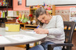 © Camelia Elisabeta Utalea/Stocksy - A woman with mental health issues making drawings in a classroom