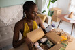 © Milles Studio/Stocksy - Black woman unpacking parcel with vitamins