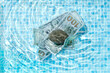 © Yaroslav Danylchenko/Stocksy - 100 dollar banknotes in pool's water.