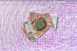 © Yaroslav Danylchenko/Stocksy - 100 euro bills pressed by stone at the bottom of pool.