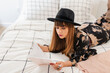 © ByLorena/Stocksy - Studious hipster woman reading from the bed