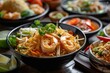 Variety of Thai food including Pad Thai with shrimp and Panang curry. Thai food
