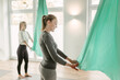 © Chris Zielecki/Stocksy - Aerial yoga instructor showing technique to group