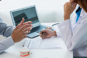 oral dentistry Female dentist in machine talking with male patient on table in clinic, dental model, dental health care according to prescription