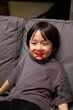 © ChaoShu Li/Stocksy - The little Asian boy put a ban sign on his mouth amusingly. on sofa