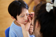 Little Asian boy, doing makeup for the performance on stage