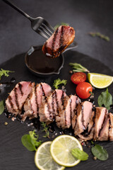 Wall Mural - sliced grilled cooked piece of tuna fillet on black stone serving board