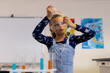 Caucasian child in a school classroom science lab examines a test tube