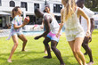 Diverse group of friends enjoy a playful game of football in a sunny backyard