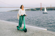 © Olga Moreira/Stocksy - Woman riding e-scooter by the river in Lisbon