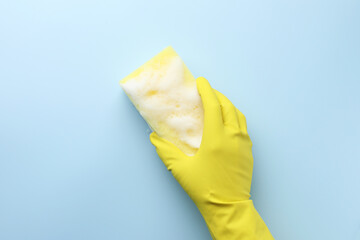 Canvas Print - Cleaner in rubber glove holding sponge with foam on light blue background, top view