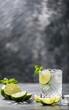 Tequila in a glass served with mint, limes and salt over dark texture background
