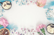 Pastelowa aranżacja w kształcie ramy z miejscem na tekst. Rama wykonana z kwiatów i drobnych ciasteczek. Widok z góry. 