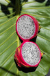 © Shava Cueva/Stocksy - A pink pitahaya split in half on a green leaf
