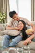© bongkarn - A lovely young Asian boyfriend is feeding popcorn to his girlfriend while watching a movie together.