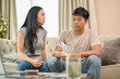 © bongkarn - An unhappy and stressed Asian wife is arguing with her husband about unexpected expenses on the sofa