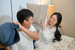 © bongkarn - A lovely and playful young Asian couple are playing a pillow fight in the bedroom.