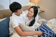 © bongkarn - A lovely young Asian couple in pajamas are hugging, playing, and cuddling in bed.